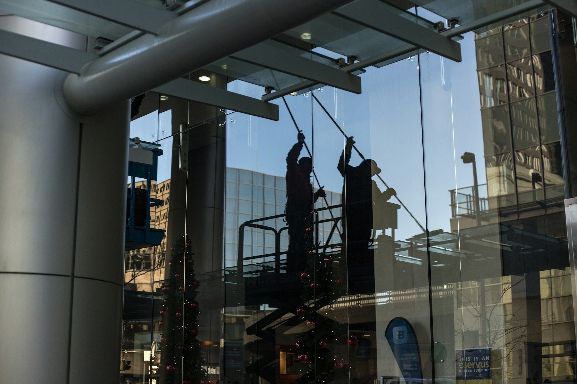 Glasreiniger auf einer Hebebühne reinigt eine große Glasfront eines Bürogebäudes